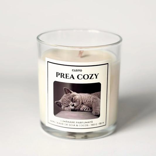 Lumanare parfumata naturala Cleito in recipient de sticla, cu eticheta alba ce contine o fotografie cu o pisica British Shorthair gri si mesajul 'PREA COZY'. Ceara de soia si cocos turnata manual.