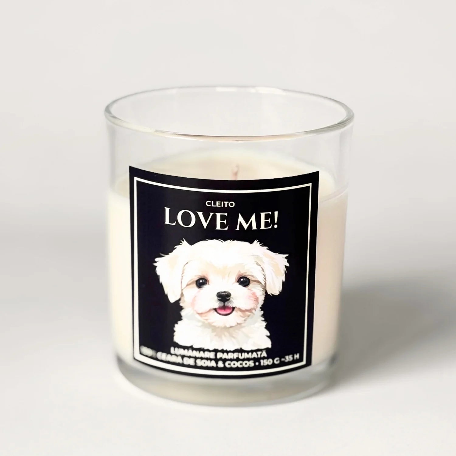 Lumânare artizanală Cleito din ceară de soia și cocos în pahar de sticlă transparentă, cu etichetă neagră premium. Eticheta prezintă o ilustrație adorabilă a unui cățel Bichon Maltese și textul alb „Cleito LOVE ME!”.