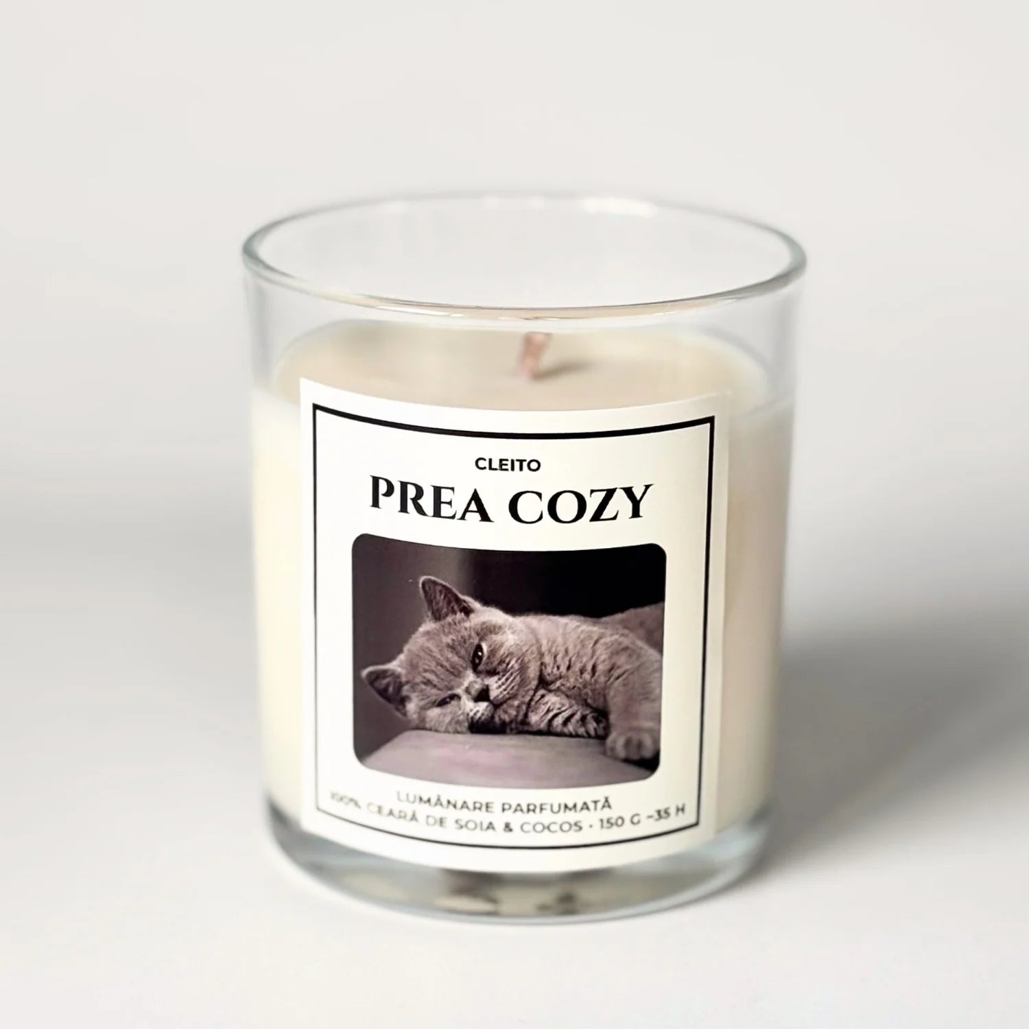 Lumanare parfumata naturala Cleito in recipient de sticla, cu eticheta alba ce contine o fotografie cu o pisica British Shorthair gri si mesajul 'PREA COZY'. Ceara de soia si cocos turnata manual.
