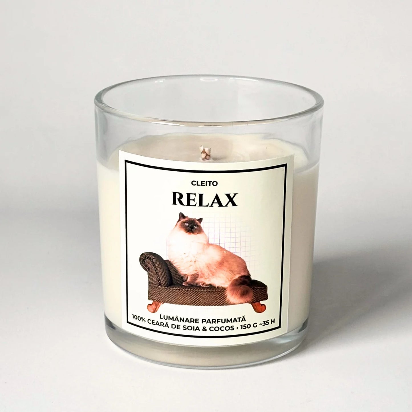 Lumanare parfumata artizanala Cleito in recipient de sticla, cu eticheta alba ce contine o fotografie cu o pisica Ragdoll pufoasa relaxandu-se pe o canapea si mesajul 'RELAX'. Ceară de soia și cocos turnata manual.