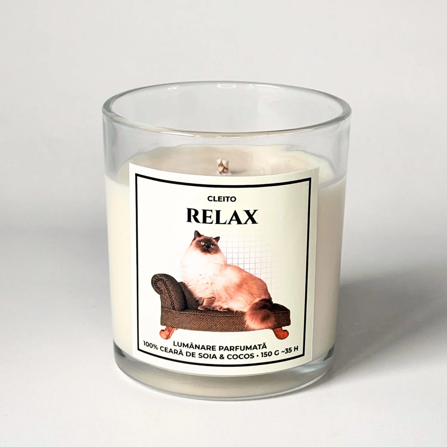 Lumanare parfumata artizanala Cleito in recipient de sticla, cu eticheta alba ce contine o fotografie cu o pisica Ragdoll pufoasa relaxandu-se pe o canapea si mesajul 'RELAX'. Ceară de soia și cocos turnata manual.